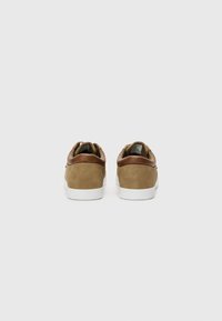 Brown suede sneakers with a contrasting brown leather heel, white rubber sole, and minimalistic design, showcasing a clean and simple style.