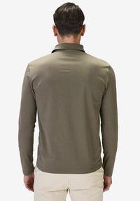 Pitkähihainen polo-paita oliivinvihreänä, jossa on kaulus ja sileä, tekstuuri. Yksinkertainen muotoilu ilman näkyviä kuvioita tai logoja.