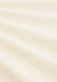 Kremowa tkanina o miękkiej, gładkiej fakturze z delikatnym prążkowaniem. Materiał wydaje się lekki i lekko elastyczny.