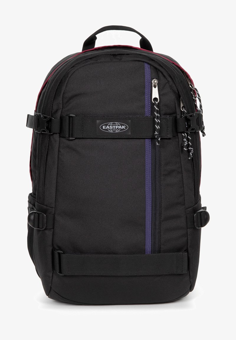 Schwarzer Rucksack aus strapazierfähigem Material, mit einem lila vertikalen Streifen, verstellbaren Trägern, einer vorderen Reißverschlusstasche und dem Eastpak-Logo.