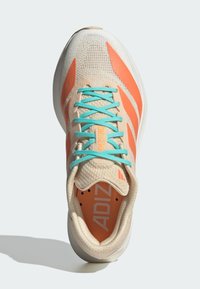 Scarpa da corsa beige e arancione con lacci turchesi, parte superiore in rete traspirante e branding "Adizero" sulla linguetta e sulla soletta.
