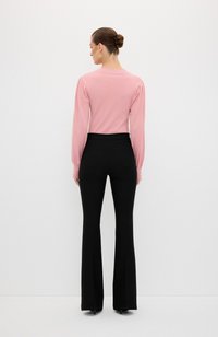 Lichtroze lange mouwen top met opbollende schouders, gecombineerd met zwarte flared broek met achterzakken en een gladde afwerking.