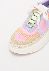 Sneaker multicolore con tomaia in tessuto intrecciato nei toni di rosa, verde e lavanda, con lacci bianchi e suola in gomma texturizzata.