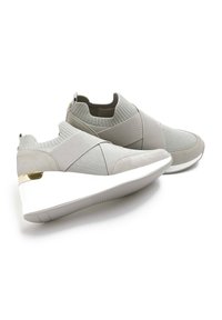 Szare buty sportowe mają połączenie teksturowanej tkaniny i miękkiej zamszowej skóry, z białą podeszwą i złotym akcentem na pięcie.