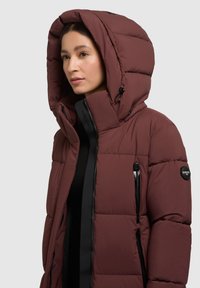 Burgunderfarbene Daunenjacke mit großer Kapuze. Verfügt über schwarze Reißverschlüsse, ein Logo-Patch und eine gepolsterte Textur für Wärme. Die Vorderseite hat ein elegantes Design.