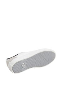 Witte sneaker met een gestructureerde rubberen zool, voorzien van zwarte en grijze suède accenten. Logo aan de zijkant en een gestroomlijnd ontwerp.