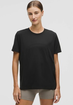 Zwarte korte mouwen t-shirt gemaakt van zachte stof. Crew neck ontwerp met een ontspannen pasvorm, met een gladde textuur en geen zichtbare patronen.