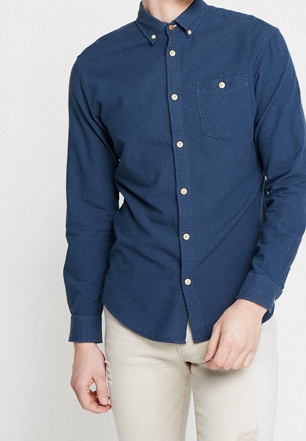 Laivastonsininen napillinen paita, jossa on teksturoitu kuvio, yksittäinen rintatasku ja vaaleat napit, valmistettu kudotusta kankaasta.