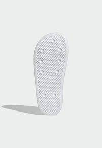 White rubber shoe sole featuring a textured surface with circular and hexagonal patterns, and multiple drainage holes for traction.
