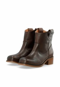 Par de botas de tobillo de cuero marrón oscuro con tacones bajos y tiradores en un fondo blanco.