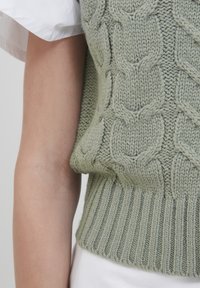 Grüner Strick-Sweater-Weste mit strukturiertem Zopf-Muster, geripptem Saum und weichem, dickem Stoff in passgenauer Silhouette.