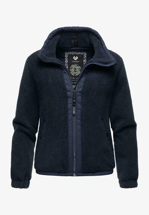 Giacca in pile blu navy con zip frontale, tessuto strutturato, colletto alto e tasche laterali. L'etichetta interna presenta una grafica di una montagna.
