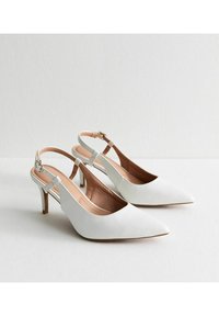 Tacchi a spillo bianchi con punta affusolata, materiale in pelle, design minimalista e tacco medio. Dettaglio con cinturino alla caviglia regolabile.