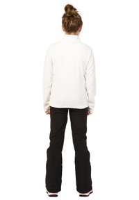 Biely fleecový pulóver s vysokým golierom v kombinácii s čiernymi rozšírenými nohavicami. Tento outfit je funkčný a vhodný na neformálne vonkajšie aktivity.