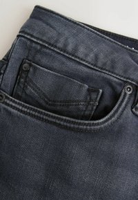 Ciemne dżinsy z denimu z przednią kieszenią i kontrastującym przeszyciem. Posiadają metalowe guziki oraz subtelny efekt prania. Klasyczny design z pięcioma kieszeniami.