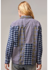 Blau-lila kariertes Hemd mit gemischten Mustern. Mit Kragen, langen Ärmeln und knöpfbaren Manschetten. Texturiert mit unterschiedlichen Karodesigns.