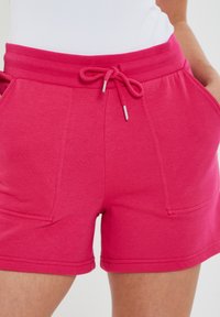 Růžové šortky z bavlněné směsi s elastickým pasem a nastavitelným šňůrkovým stahováním, dvěma bočními kapsami a dvojitě šitými lemy.