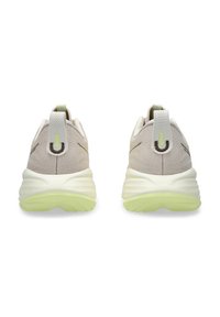 Lichtbeige hardloopschoenen met een gestructureerde bovenkant, witte tussenzool en zachte groene buitenzool. Voorzien van een trekband en subtiele accenten.
