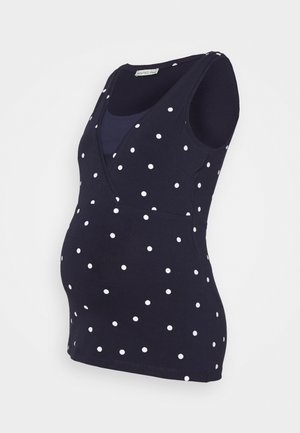 Donkerblauwe mouwloze zwangerschaps top met witte stippen en een gelaagd V-hals ontwerp.