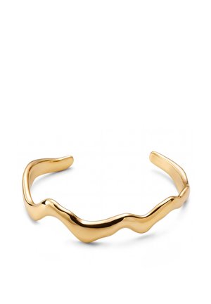 Kultaisen sävyn avoin kalterirannekoru, jossa on abstrakti, aaltoileva muotoilu ja sileä, kiillotettu pinta valkoisella taustalla.