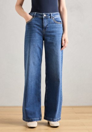 Jean en denim bleu à jambes larges, avec un design à cinq poches, des accents de couture subtils et une fermeture à bouton à la taille.