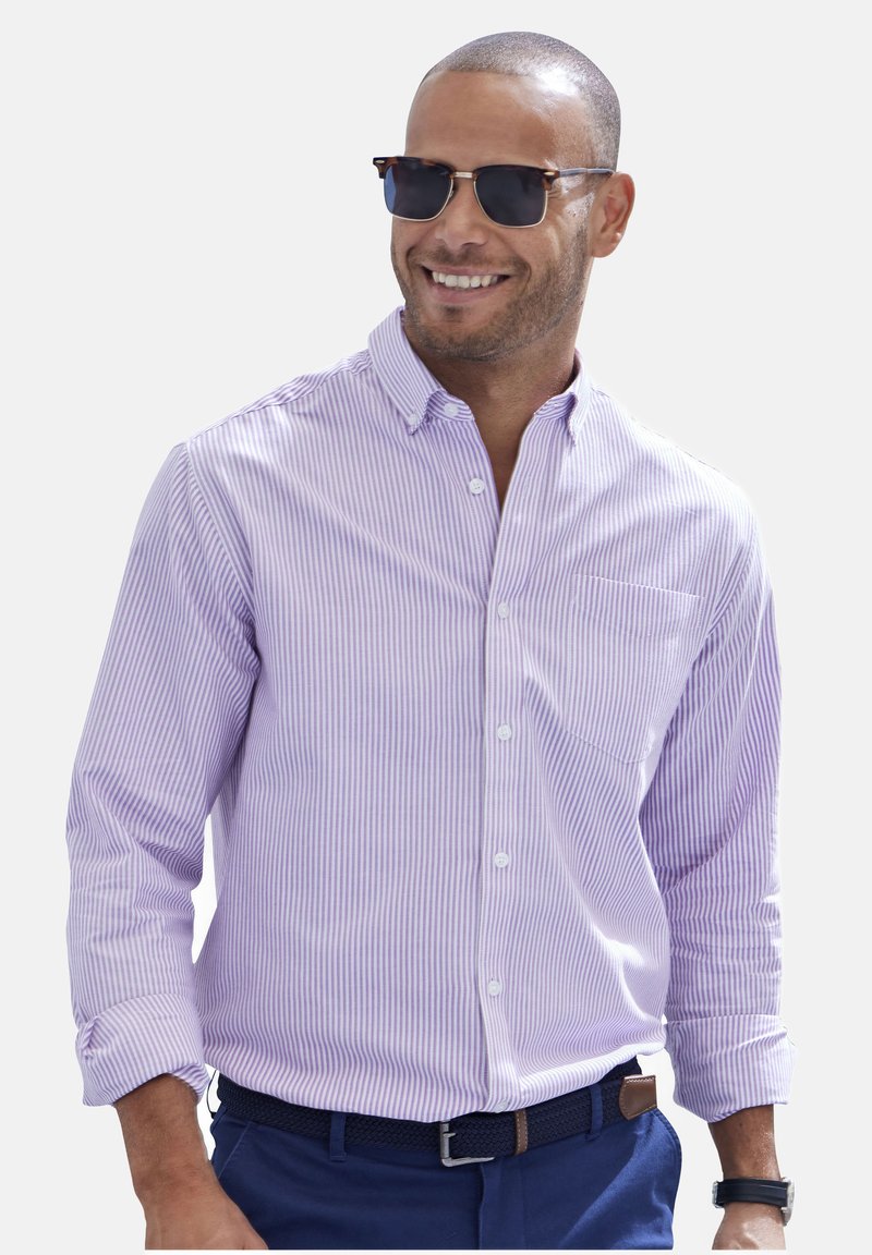 Helllila gestreifte Button-Up-Hemd mit langen Ärmeln, einer einzigen Brusttasche, kombiniert mit marineblauen Hosen und Sonnenbrille.