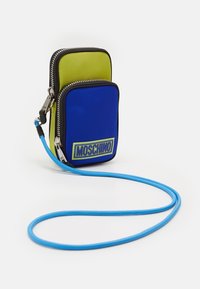 Borsa multifunzionale in nylon, con parte superiore verde e parte inferiore blu, chiusura con zip, rifiniture nere e tracolla blu con logo Moschino.