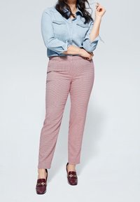 Lichtblauw denim shirt met twee borstzakken, gecombineerd met strakke rood-wit gerenst broek en donkergekleurde loafers.