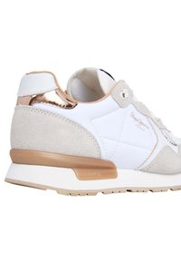 Witte sneaker met beige suède accenten, metallic gouden hiel, textuurmaterialen en een rubberen zool met merkdetail aan de zijkant.