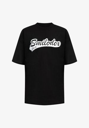 Schwarzes Baumwoll-T-Shirt mit kurzen Ärmeln, das ein weißes, geschwungenes "Smilodox"-Logo auf der Brust trägt. Lockerer Schnitt und Rundhalsausschnitt.