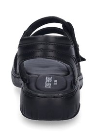 Černá kožená sanda se otevřenou zadní částí, polstrovanou stélkou, nastavitelným popruhem a strukturovanou podešví. Obsahuje značený vnitřek a minimální prošívání.