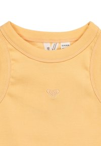 Camiseta de tirantes amarilla con un escote redondo y un pequeño logo de corazón bordado en el pecho. Textura suave y diseño ajustado.