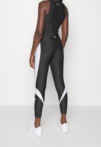 Black sports tank top and leggings with white accents. Leggings feature a geometric pattern, smooth texture, and form-fitting design.
