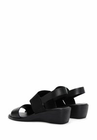 I sandali wedge neri presentano un tacco wedge testurizzato, punta aperta e larghe fasce elastiche per una vestibilità sicura. Materiale in pelle liscia e tessuto.