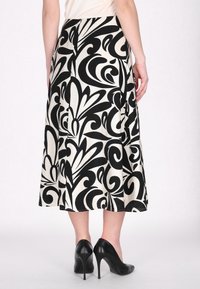 Fustă cu model alb-negru ce prezintă mari desene florale și abstracte, cu o siluetă evazată și o lungime până la genunchi. Pură cu tocuri negre.