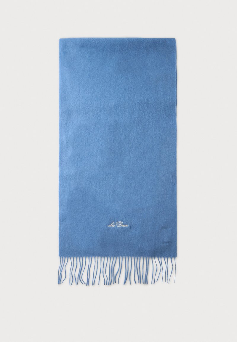 Écharpe rectangulaire bleu clair avec bords à franges et petit texte brodé près du bas, au centre, sur fond blanc.