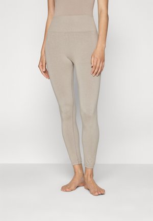 Beige Leggings mit hohem Bund, aus dehnbarem Stoff gefertigt. Das Design ist eng anliegend und verjüngt sich am Knöchel ohne sichtbare Nähte.