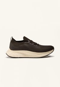 Zwarte gebreide sneaker met golvende patronen, vetersluiting aan de voorkant, gewatteerde kraag en dikke witte textuurzool op een plain witte achtergrond.