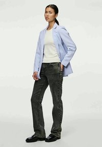 Ανοιχτό μπλε σακάκι, άσπρη μπλούζα και σκούρα γκρίζα τζιν. Το σακάκι έχει κομψό σχέδιο, τα τζιν είναι ίσιας γραμμής. Γυαλιστερές μαύρες παπούτσες.