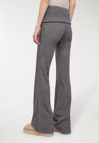 Szare spódnice w żakardowym fasonie wykonane z miękkiego materiału, z szerokim pasem i gładką teksturą, w połączeniu z jasnymi klapkami.