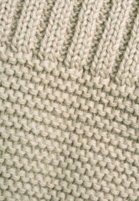 Tessuto a maglia di colore crema con un design strutturato e spesso che presenta motivi a coste alternate e lisci. Texture morbida, simile alla lana.