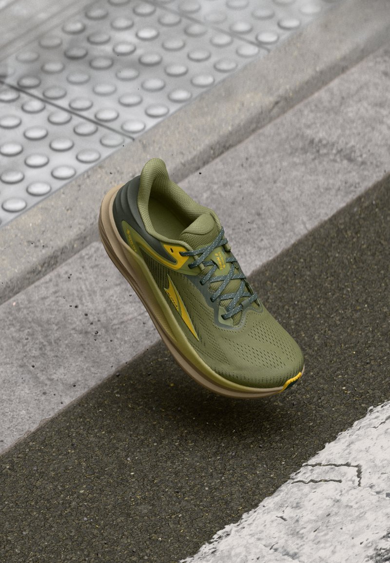 Baskets de course vertes avec une tige en mesh, un design texturé, des accents jaunes et une semelle rembourrée. Présente des lacets et une forme de orteil arrondie.