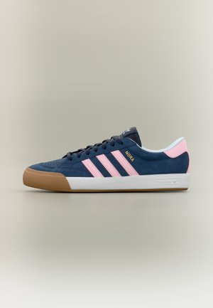Σκούρο μπλε αθλητικό παπούτσι Adidas με ροζ ρίγες, σόλα από καουτσούκ, λευκό μεσαίο μέρος και τη λέξη «NORA» σε χρυσά γράμματα στο πλάι.