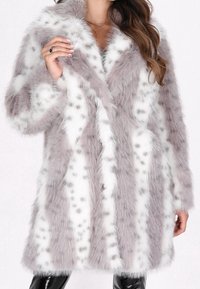 Faux fur jakke med et grå og hvidt farvemønster og plettede accenter. Den har en blød tekstur, brede revers og en knaplukning.