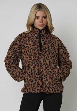 Pull en polaire marron avec imprimé léopard noir, col montant et fermeture éclair sur le devant. Comprend des poches avant et un tissu texturé et duveteux.