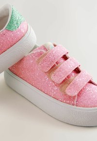 Roosa sädeluskingad kolme Velcro rihmaga, tekstureeritud pind ja valge kummitald. Roheline aktsent kanna piirkonnas.