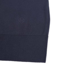 Maglione lavorato a maglia blu navy con orlo a coste e un piccolo logo a diamante in rilievo. Texture morbida con una finitura liscia.