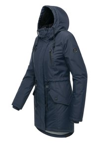 Granatowa parka z kapturem wyłożonym sztucznym futrem, regulowanym paskiem w talii oraz wieloma kieszeniami. Wykonana z wodoodpornego materiału i wyposażona w zamki błyskawiczne.