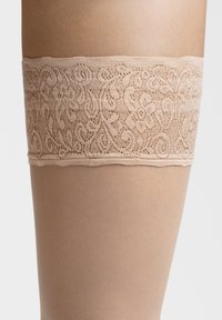 Nude thigh-high strømper med intrikate blonder i toppen, der har blomstermønstre og en glat, gennemsigtig bensektion.