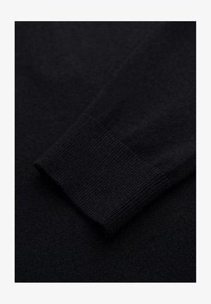 Nahaufnahme eines schwarzen Pulloverelements, das ein geripptes Bündchen und eine glatte Textur aufweist, aus Strickstoff gefertigt für Wärme und Komfort.